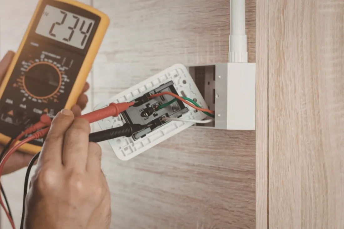 Elektriker måler spændingen i en stikkontakt med et multimeter