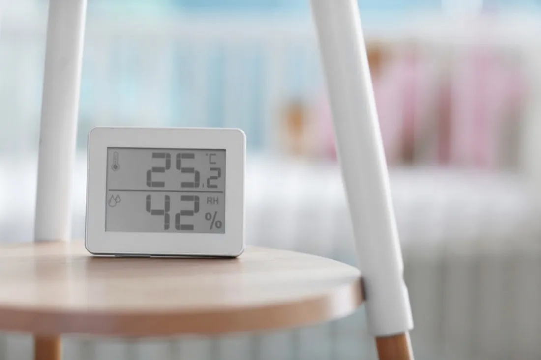 Digitalt hygrometer på et bord viser 25,2 grader og 42 procent luftfugtighed